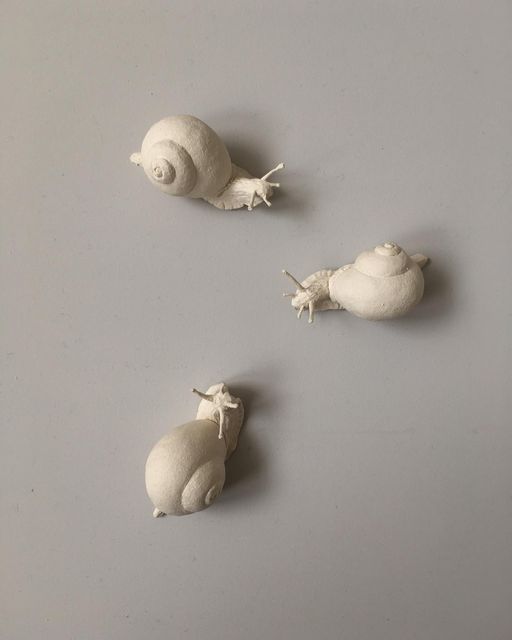 three small white figurines sitting next to each other on a gray table top