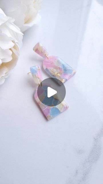 a white flower sitting next to a pair of earrings on top of a countertop