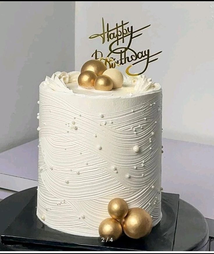 there is a white cake with gold decorations on the top and two balls in the middle