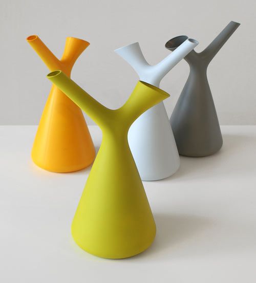 three different colored vases sitting next to each other on a white surface, one is yellow and the other two are gray