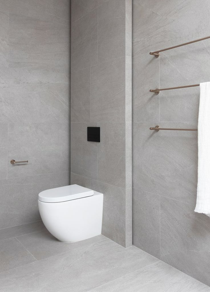 a white toilet sitting in a bathroom next to a towel rack