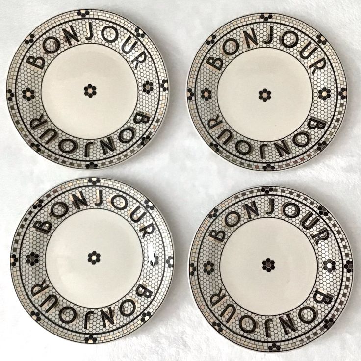 four black and white plates with the words bonjou on each one, in different languages