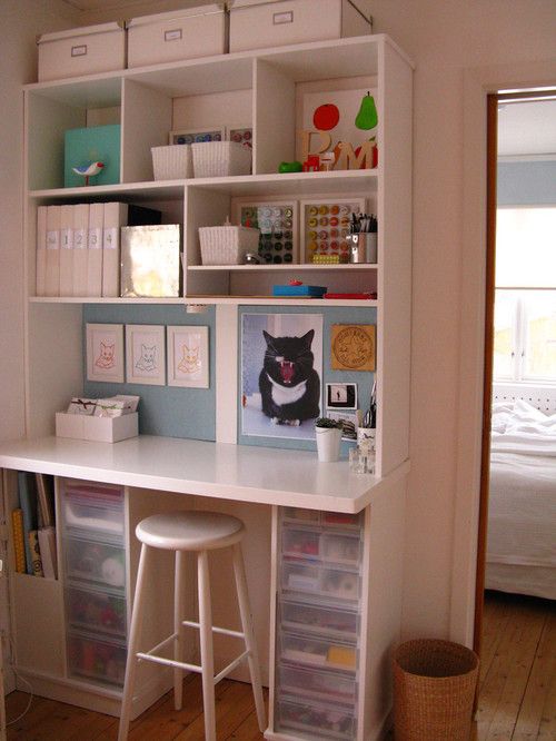 a white desk topped with lots of drawers next to a wall mounted book shelf filled with books