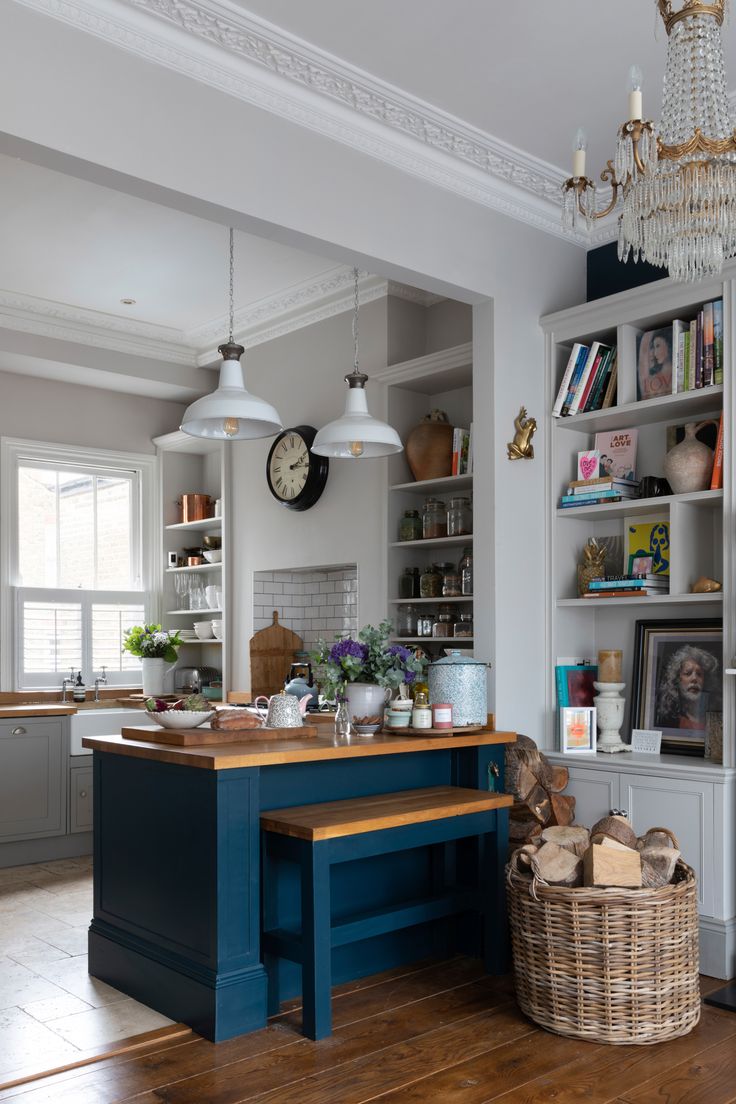 a kitchen with a blue island and wooden counter top next to a white bookcase