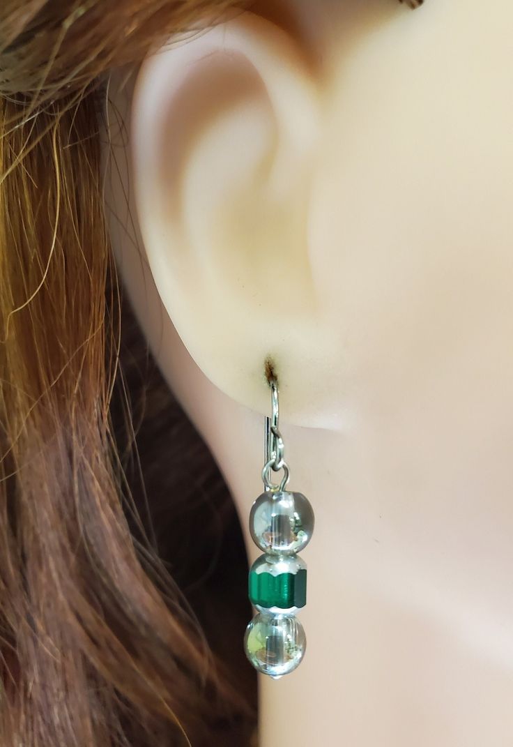 Green Cathedral Bead Earrings have a green cathedral bead at center with silver ends. Above and below are transparent round beads with hint of green. Beads dangle from silver tone ear wires. Designed and created by staff at Takeen Arts Studio. Item E1161. Green Glass Dangle Jewelry, Sterling Silver Jewelry With Green Dangling Beads, Green Nickel Free Dangle Earrings, Nickel-free Green Dangle Earrings, Green Nickel-free Dangle Earrings, Green Adjustable Dangle Crystal Earrings, Adjustable Green Crystal Dangle Earrings, Elegant Green Hypoallergenic Beaded Earrings, Nickel-free Green Drop Crystal Earrings