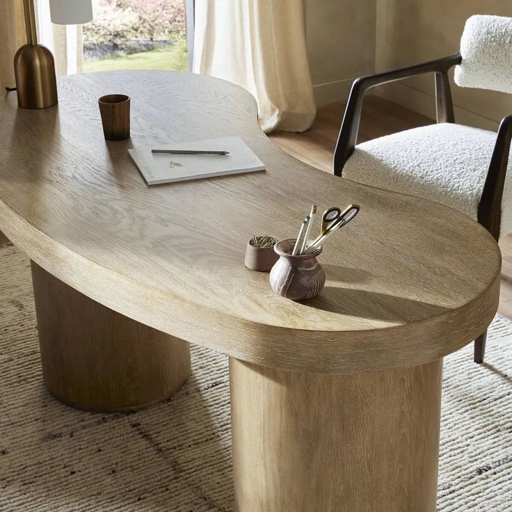 a wooden table sitting in the middle of a living room next to a white chair