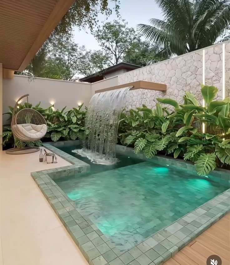 a pool with a waterfall in it surrounded by greenery and lights on either side