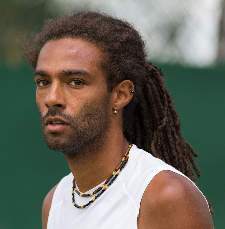 a man with dreadlocks on his head holding a tennis racket