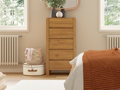 a bedroom scene with focus on the dresser and bed, which has a plant in it