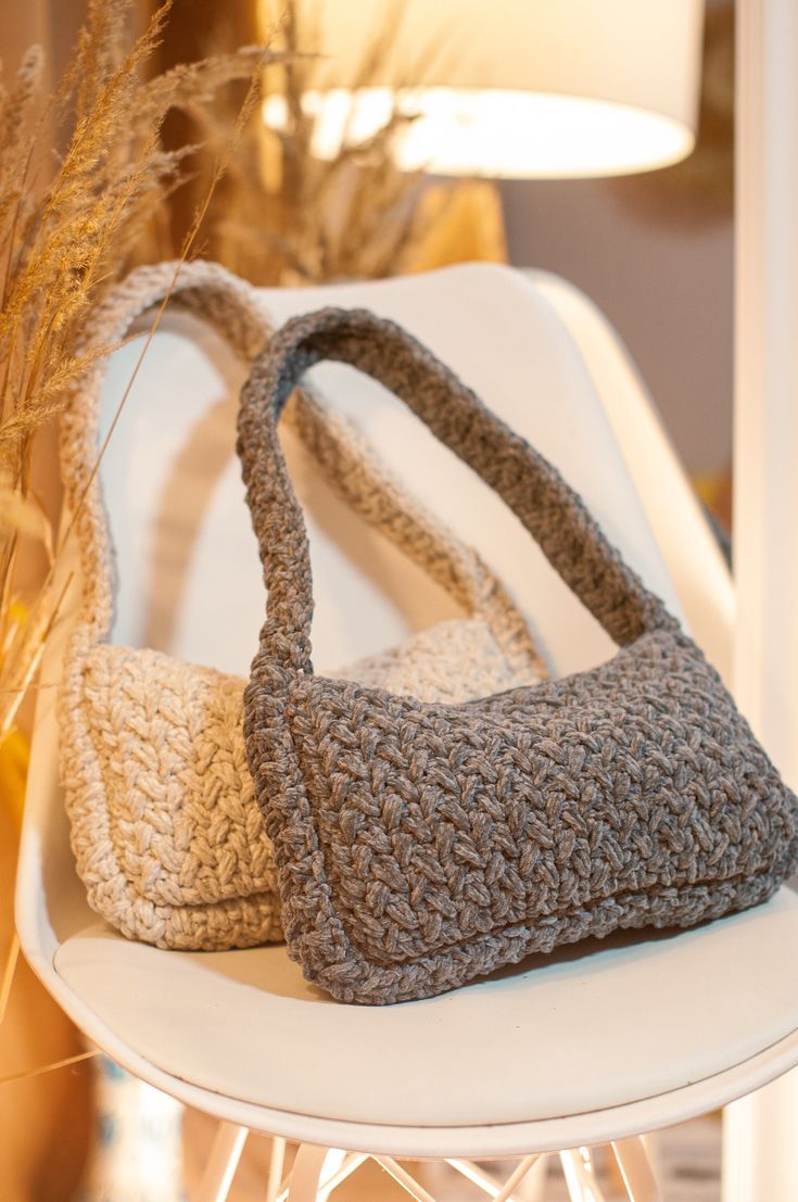 two crocheted purses sitting on top of a white chair