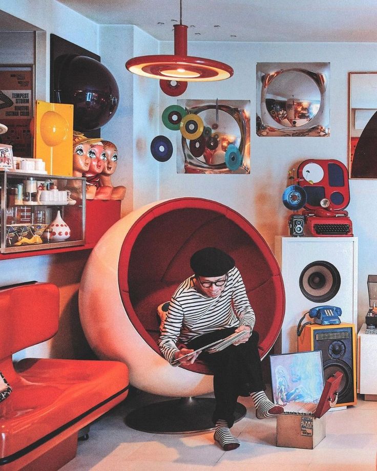 a person sitting in a room with many items on the wall and one is reading