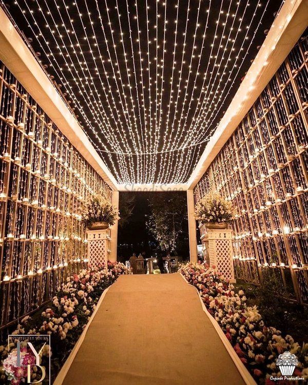 an indoor walkway with lights and flowers on the sides, along with potted plants