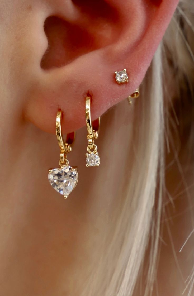 This CZ Heart Huggie ﻿is a fun yet sophisticated earring. These would look darling alone or stack with some of our studs to create a shiny layered look. Materials: Cz heart charm, gold plate brass huggies SKU: E1545G Stacked Earrings Gold, Heart Earrings Gold, Dainty Huggie Earrings With Heart Charm, Gold Dainty Heart Earrings With Cubic Zirconia, Gold Cubic Zirconia Heart Earrings In Dainty Style, Dainty Gold Heart Earrings With Cubic Zirconia, Gold Plated Huggie Earrings With Heart Charm, Dainty Gold Earring Stack, Cute Earring Stacks