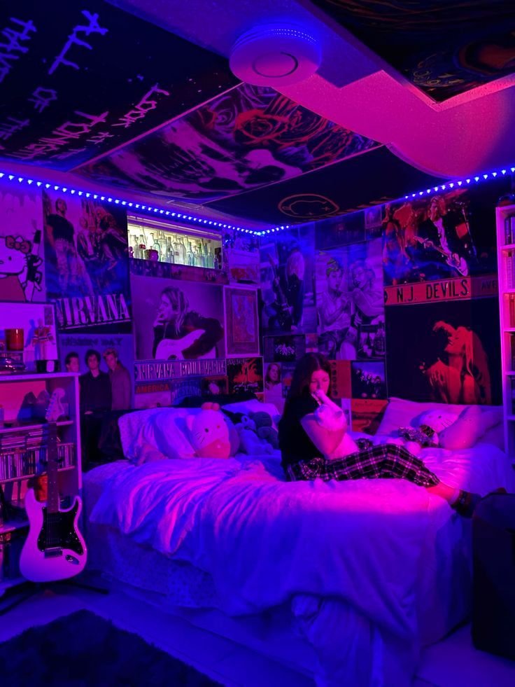 a woman sitting on a bed in a room with purple lights and posters all over the walls