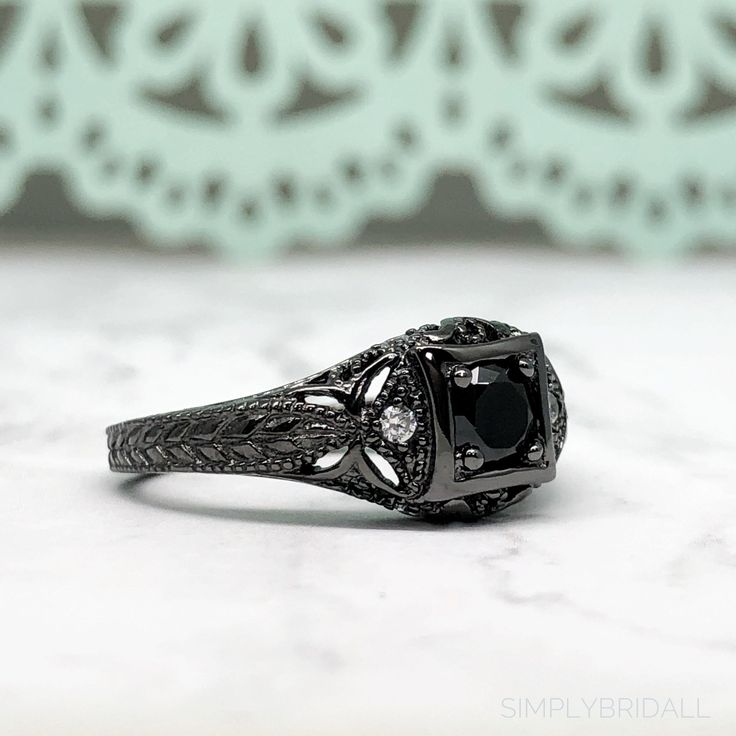 M A T E R I A L S ~ Solid Sterling Silver ~ Black Rhodium S T O N E S Cruelty Free ~ Simulated Black Diamond ~ Center Stone : 0.45ct ~Side White Diamonds: 0.12ct D I M E N S I O N S ~ Band: 3.00mm ~ Setting: 5.75mm Height 9.00mm Width R I N G C A R E ~ Simple instructions to care for the ring is not expose your jewelry to chemicals like bleach, chlorine, hairspray, to avoid chemical reactions or breakdown of materials. (Just as you would with any jewelry) ~ Try not wear your jewelry in the showe Formal Black Rings With Black Diamonds, Classic Black Ring With Halo Setting, Classic Black Jewelry With Center Stone, Classic Black Rings With Accent Stones, Classic Black Rings For Anniversary, Classic Black Jewelry With Accent Stones, Black Jewelry With Halo Setting For Formal Occasions, Black Spinel Jewelry For Anniversary, Classic Black Diamond Ring With Black Enamel