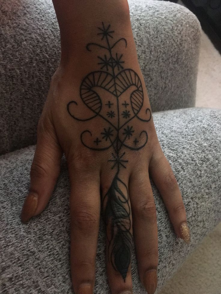 a person's hand with a tattoo on it and a feather in the middle