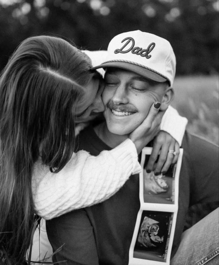 black and white photograph of a man kissing a woman's face with an award in his hand