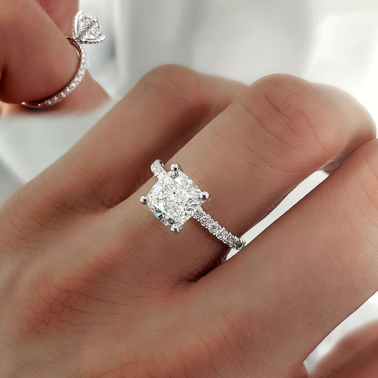 a woman's hand with a diamond ring on top of her finger and an engagement band