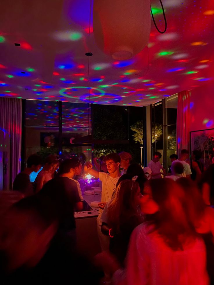 a group of people standing in a room with colorful lights on the ceiling and floor