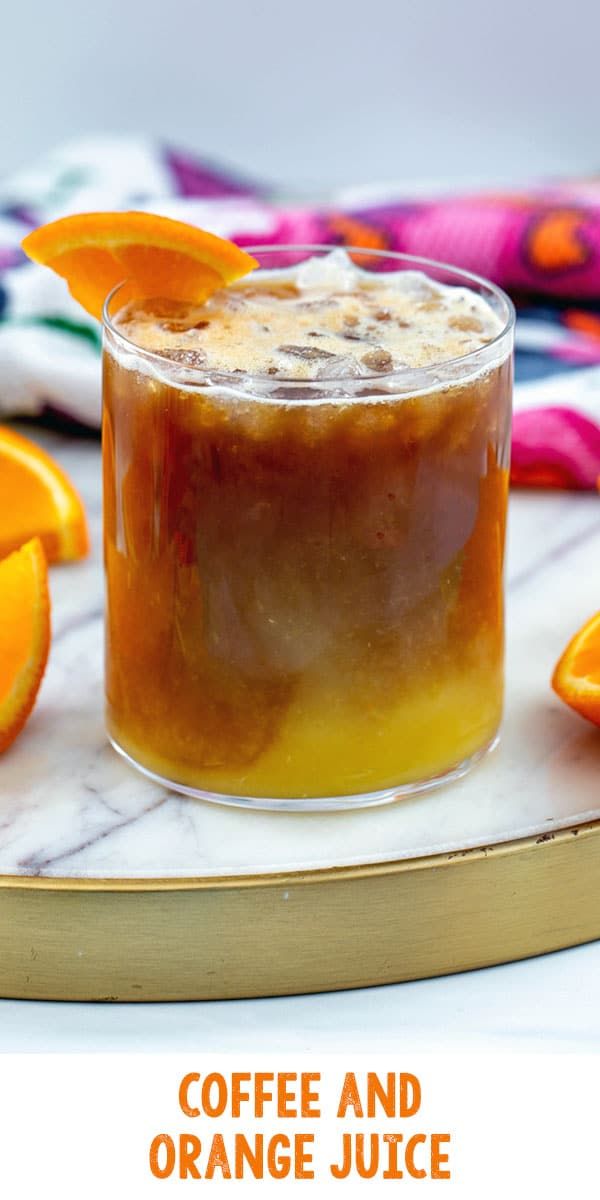 coffee and orange juice in a glass on a marble platter with sliced oranges