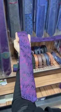 a purple tie sitting on top of a wooden shelf in front of a desk filled with ties