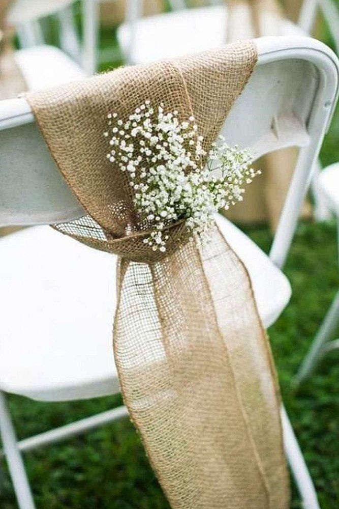 a bouquet of baby's breath sits on the back of a white folding chair