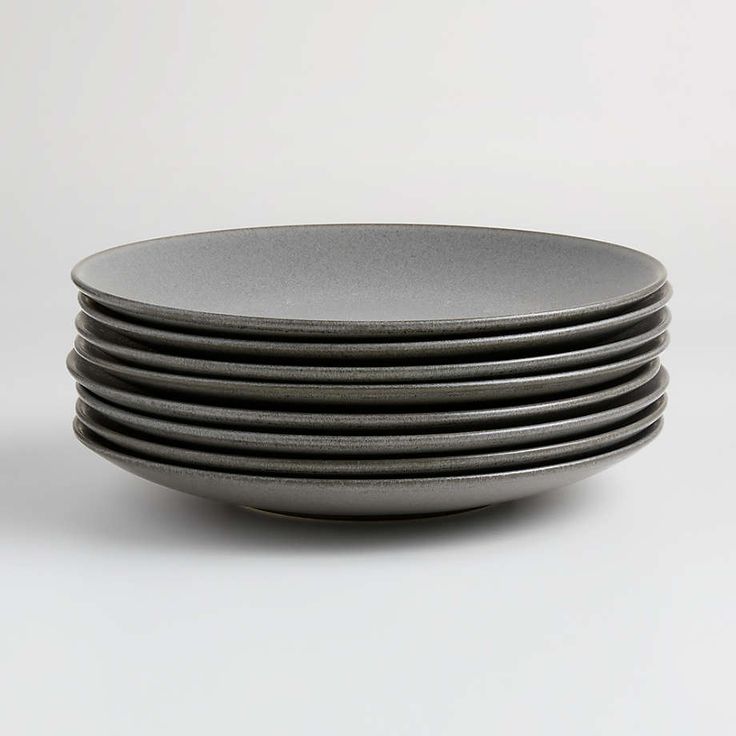 stack of black plates sitting on top of each other in front of a white background