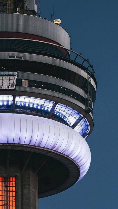 the top of a tall tower with lights on it's sides and windows lit up at night