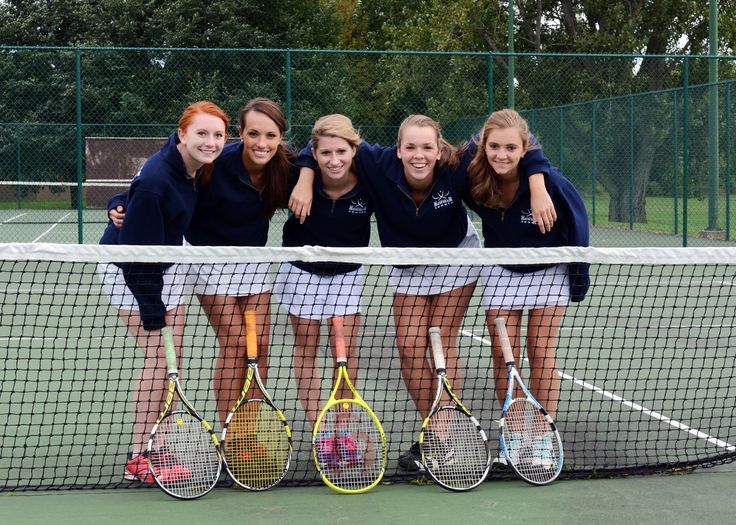 four girls are posing with tennis rackets on the court