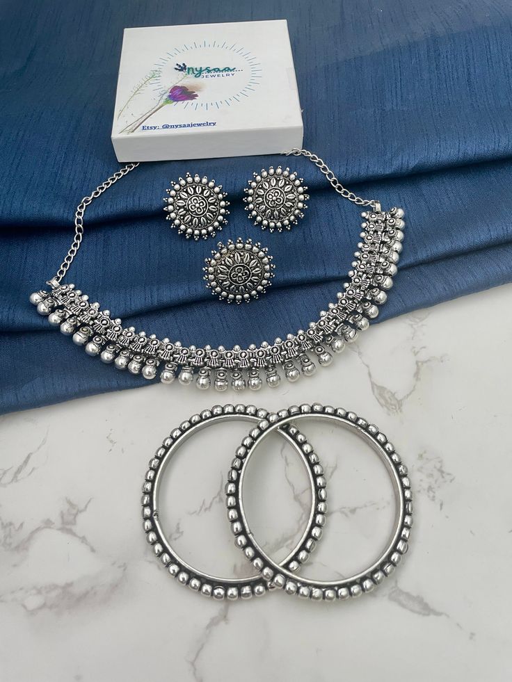 Elegant Silver Sets For Gift, Elegant Silver Sets For Gifts, Silver Necklace With Matching Earrings For Diwali, Round Matching Earrings For Diwali, Matching Round Earrings For Diwali, Round Metal Jewelry Sets With Hand Set Stones, Festive Jewelry With Oxidized Finish, Festive Oxidized Round Jewelry, Festive Round Oxidized Jewelry