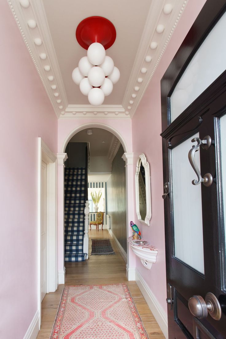 the hallway is painted pink and has white balloons hanging from it's ceiling, along with an area rug