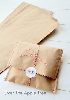 some brown paper bags tied with twine on white wood floored area and one has a tag that says, over the apple tree