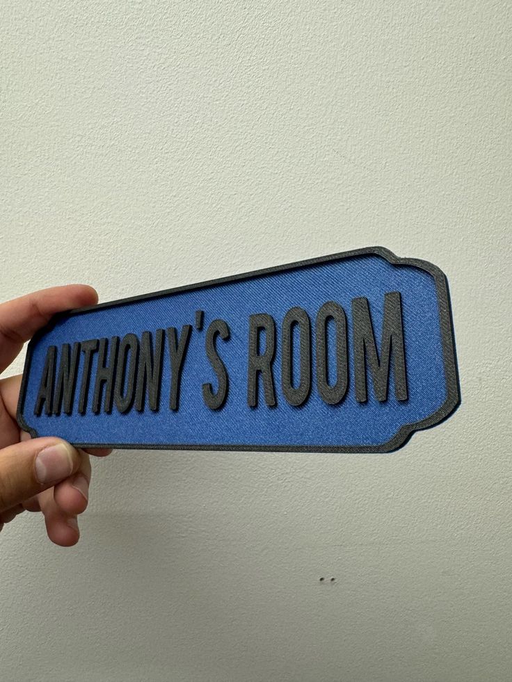 a person holding up a blue and black sign that says anthony's room on it