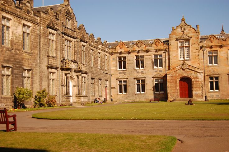 an old building with a red door and two benches in front of it on a sunny day