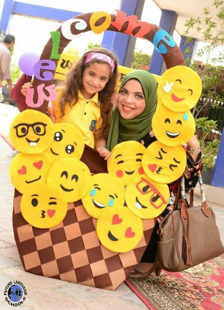 two women pose for a photo in front of an ice cream cone with smiley faces on it