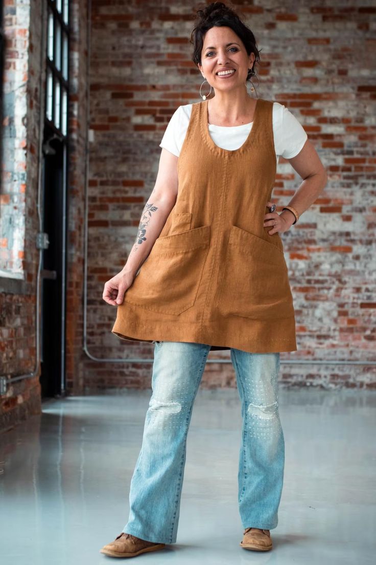 a woman standing in front of a brick wall with her hands on her hips and smiling