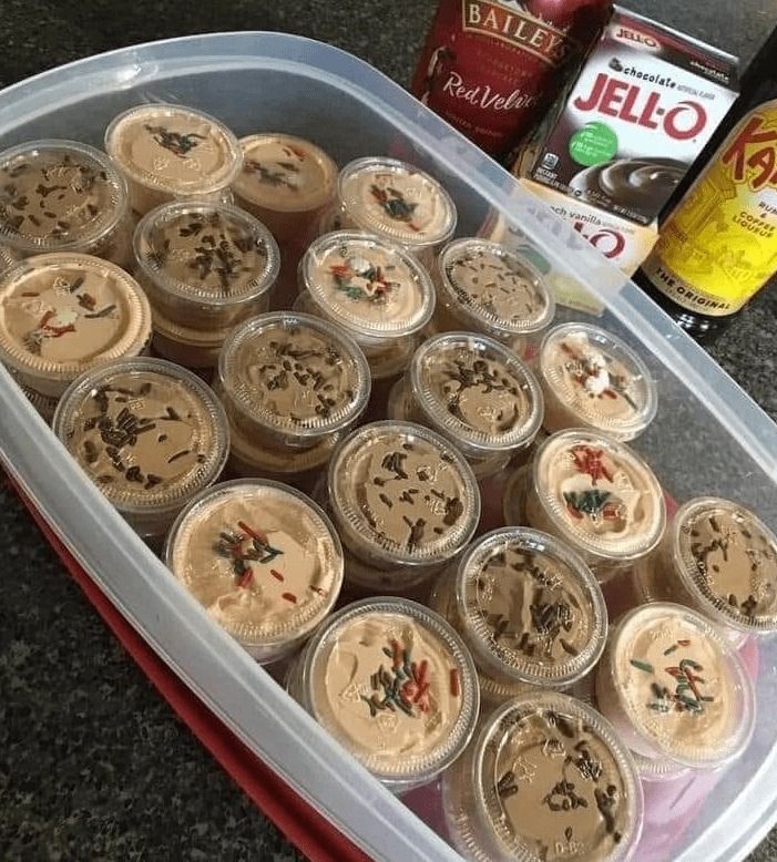 there are many cupcakes in the plastic container on the counter next to beer