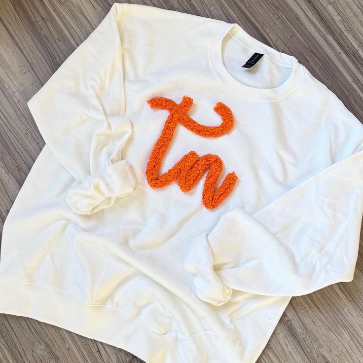 Pullover embroidered with chenille The option pictured is while with orange text. We also have orange with white text available.  *We use only the highest quality Heavy Blend Gildan Unisex Sweatshirts Laundering: wash inside out and line dry for best results. White Sweatshirt With Embroidered Graphics For Team Spirit, White Team Spirit Sweatshirt With Embroidered Graphics, White Collegiate Sweatshirt With Custom Embroidery, White Varsity Sweatshirt With Embroidered Graphics, White Cotton Sweater With Letter Embroidery, White Custom Embroidered Top For College, White Cotton Sweater With Embroidered Text, White Collegiate Sweatshirt With Letter Embroidery, Custom Embroidered White T-shirt For Fall