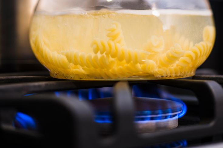 a bowl of noodles is sitting on top of an oven burner with the lid open