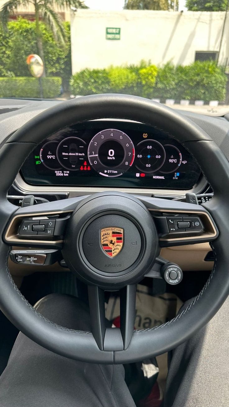 the interior of a car with steering wheel controls and dashboard gauges on display in front of palm trees