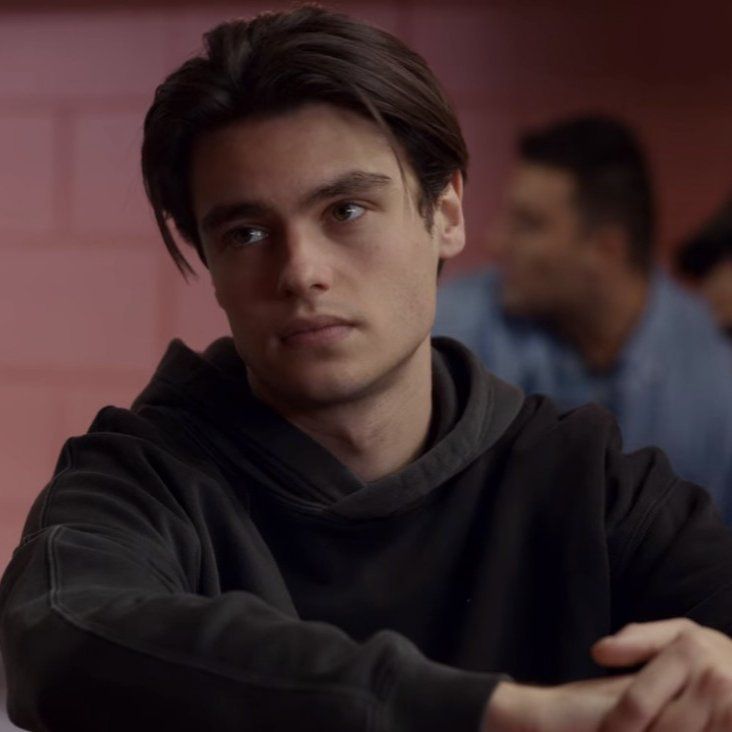 a young man sitting at a table with his arms crossed and looking off to the side