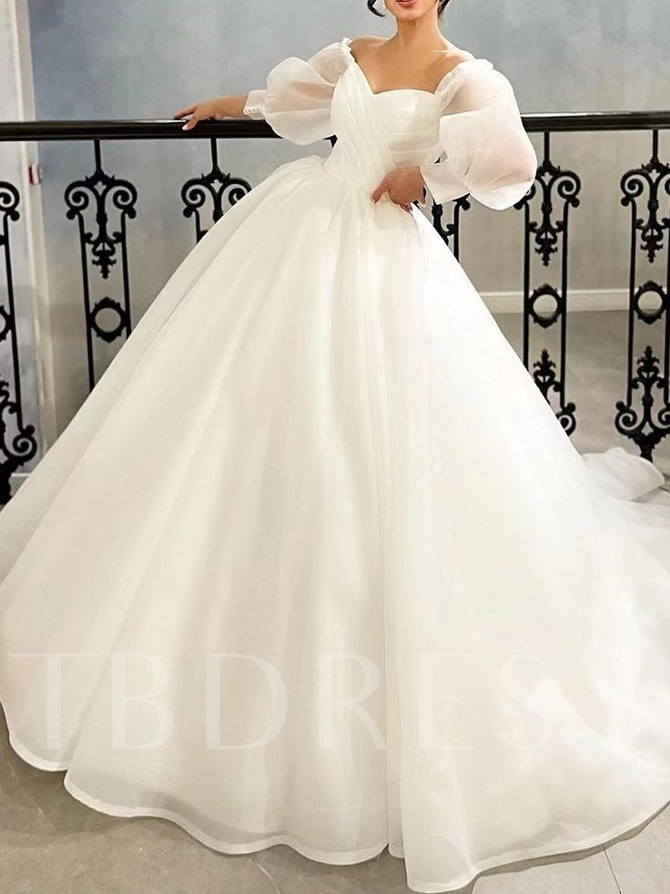 a woman in a white wedding dress standing on a balcony with her hands on her hips