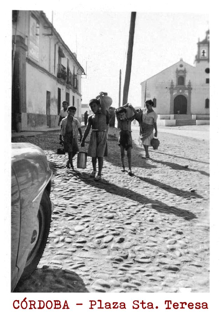 black and white photograph of people walking down the street with cars parked in front of them