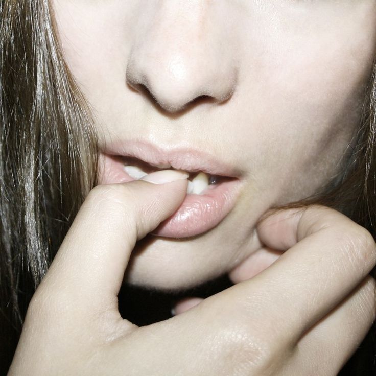 a close up of a person holding their hand to her mouth with both hands on the lip