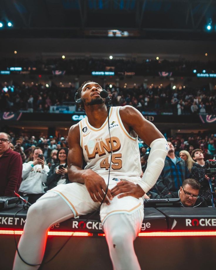 a man sitting on top of a bench in front of a crowd at a basketball game