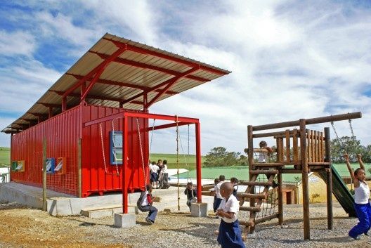 children playing on a playground with a red structure and play equipment in the foreground