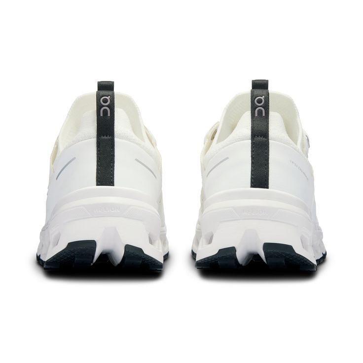 a pair of white sneakers with black straps on the side and one shoe in the middle