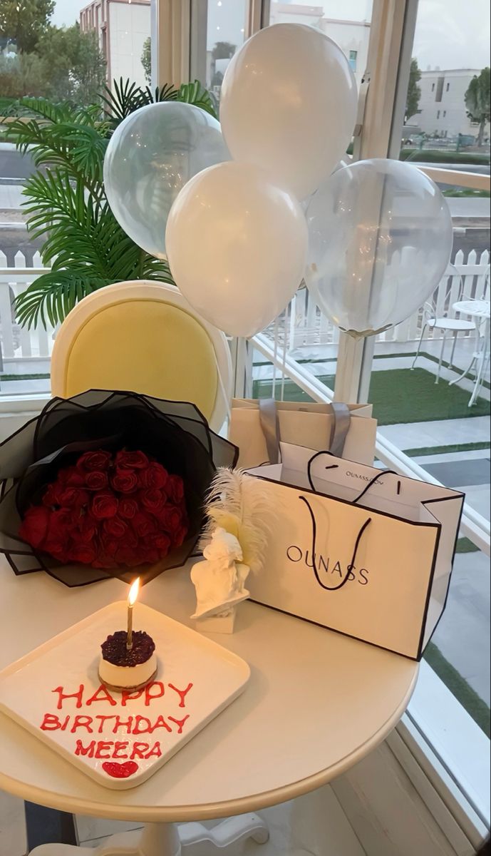 a birthday cake on a table in front of balloons and greeting cards for someone's special day