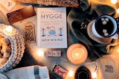 a table topped with books and candles next to a cup of hot chocolate on top of a blanket