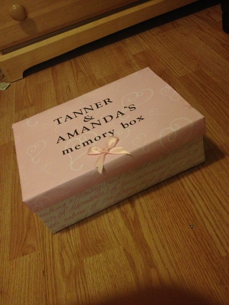 a pink box sitting on top of a wooden floor next to a drawer with a ribbon